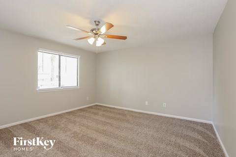 the spacious living room with ceiling fan and carpet