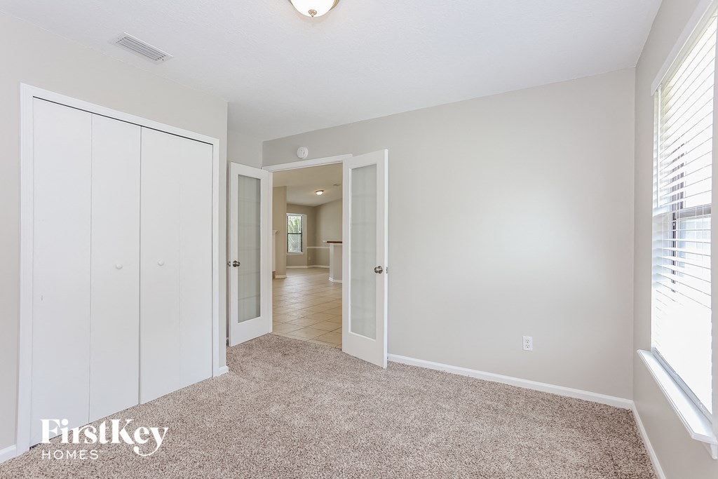 a bedroom with white closets and a carpeted floor