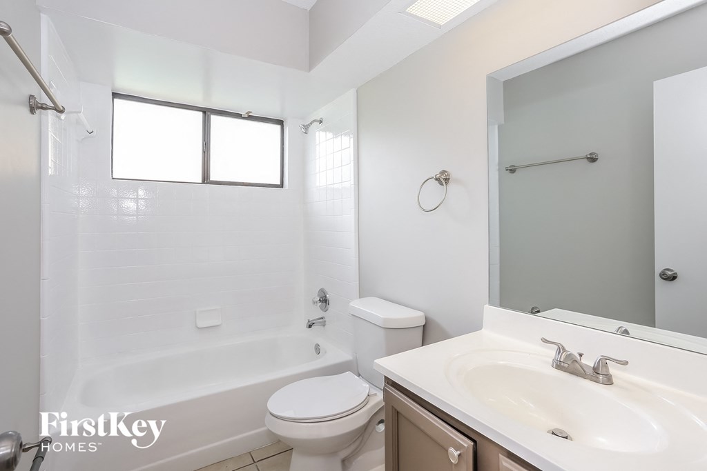 a white bathroom with a toilet sink and tub and a mirror