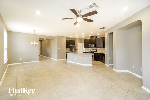 an empty living room with a ceiling fan and a kitchen
