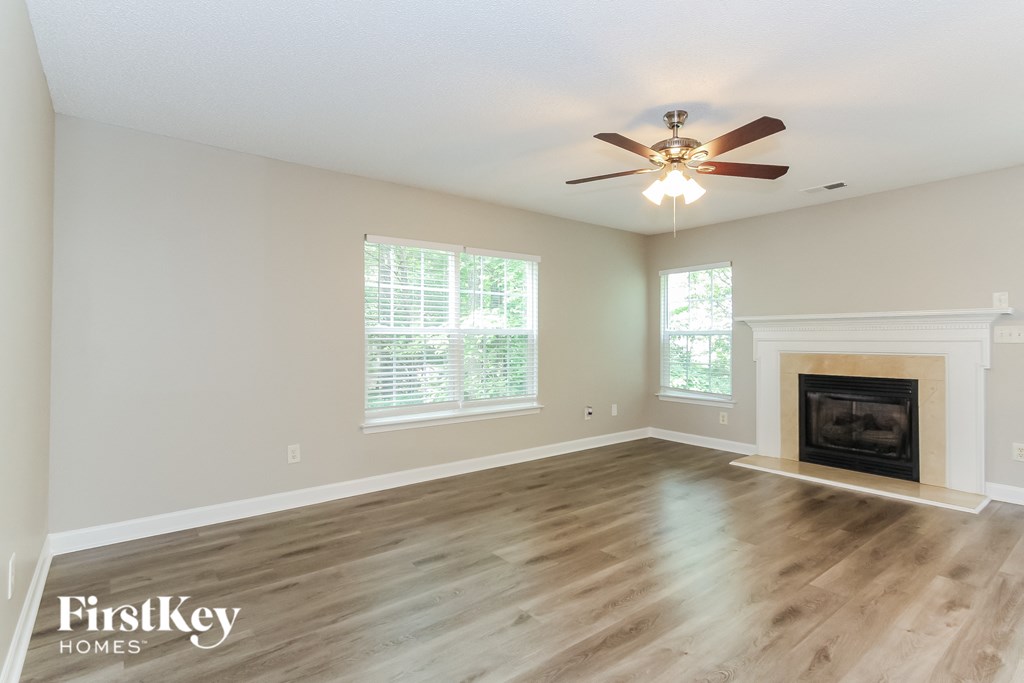 the living room with a fireplace and a ceiling fan