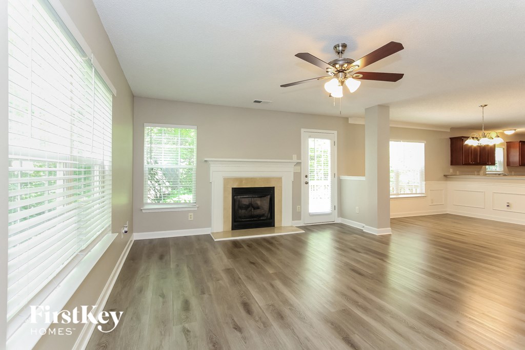 an empty living room with a ceiling fan and a fireplace