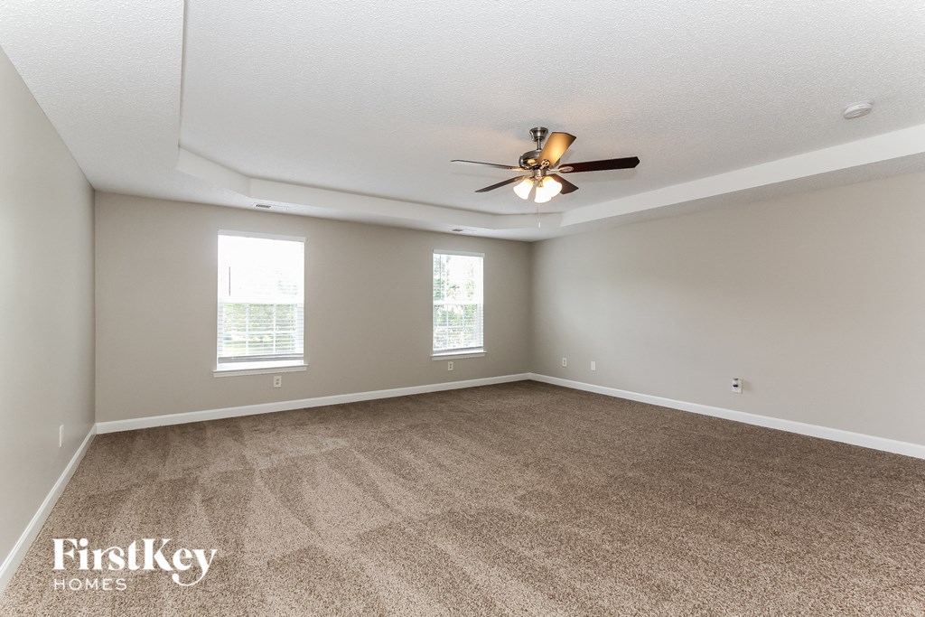 a living room with carpet and a ceiling fan