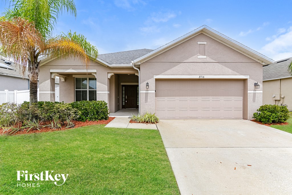 A house with a garage and a driveway in front of it.