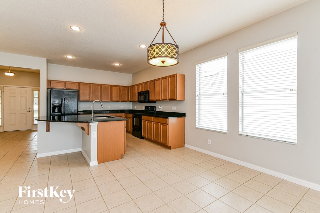 A kitchen with a white ceiling and a hanging light fixture.