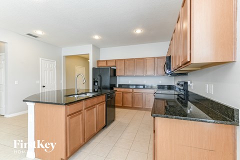 A kitchen with wooden cabinets and black countertops.