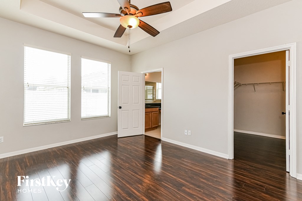 A spacious room with a ceiling fan and wooden floors.