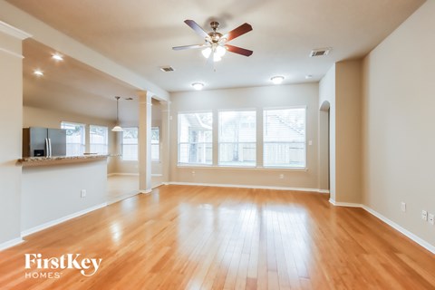 A spacious room with wooden floors and a ceiling fan.