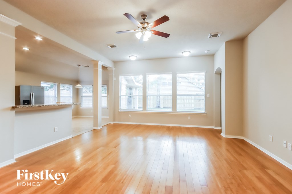 A spacious room with wooden floors and a ceiling fan.