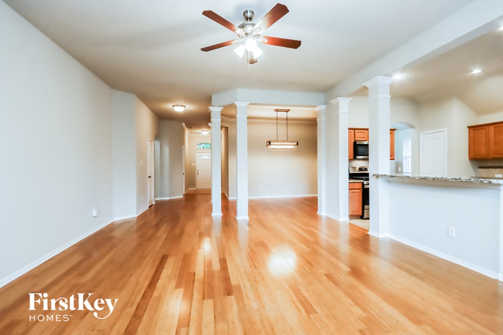 A spacious room with wooden floors and a ceiling fan.
