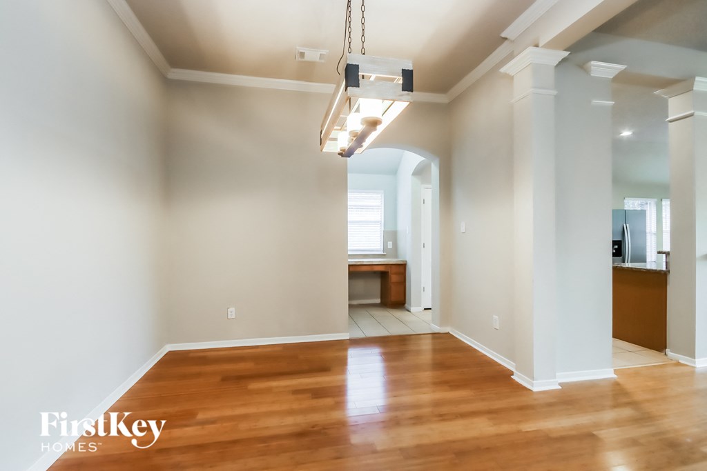 A large empty room with wooden floors and a light hanging from the ceiling.