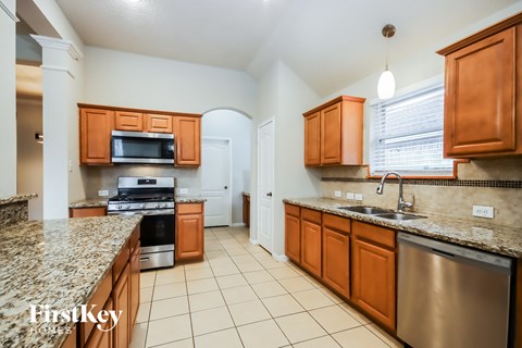 A kitchen with brown cabinets and granite countertops.