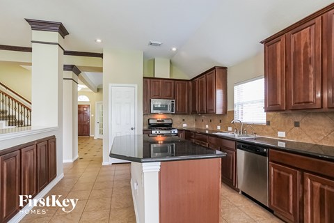 A kitchen with brown cabinets and a black countertop.
