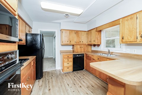 A kitchen with wooden cabinets and a black fridge.