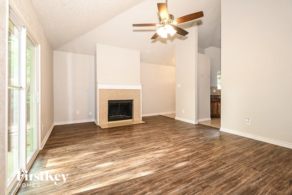 an empty living room with a fireplace and a ceiling fan