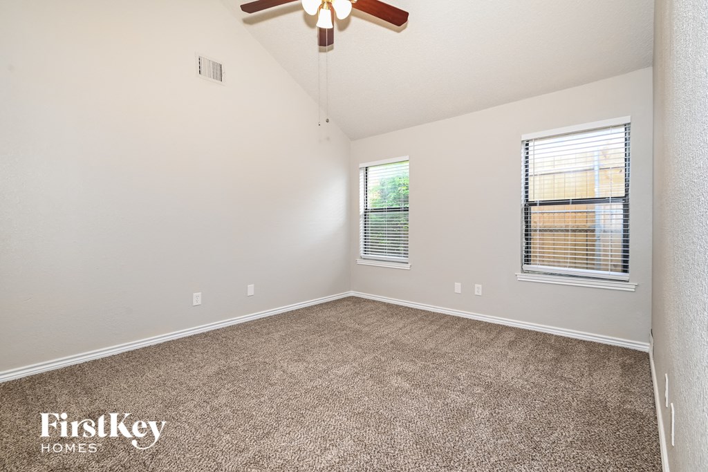 the spacious living room with carpeting and a ceiling fan
