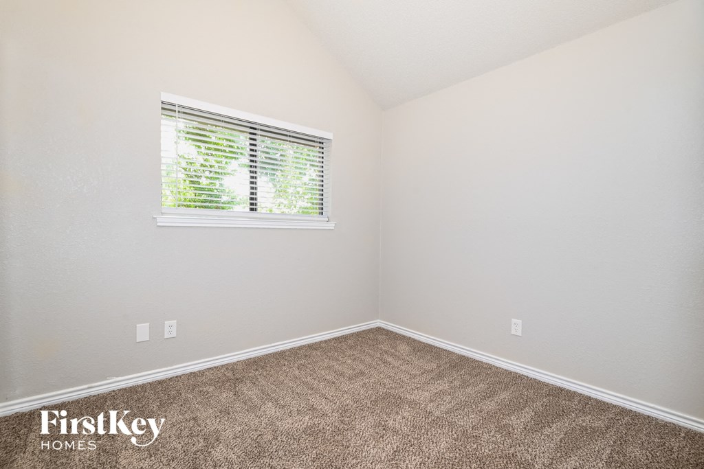 the bedroom of a small house with carpet and a window