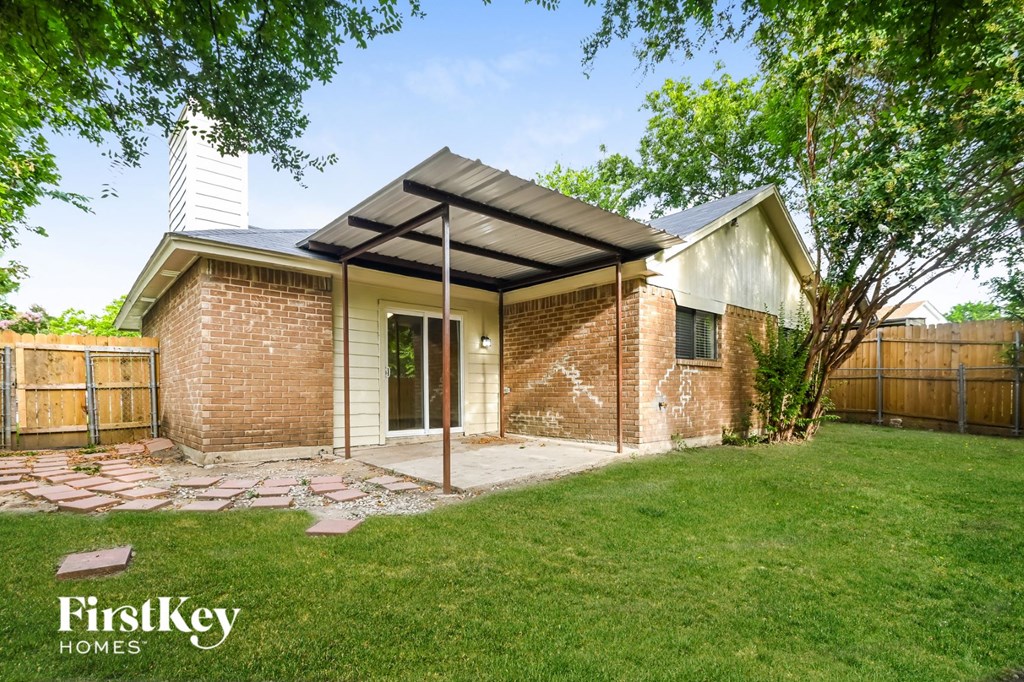 a small brick house with a porch and a grassy yard