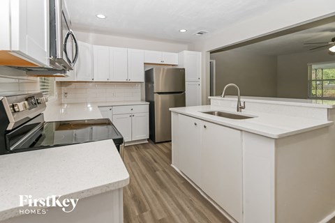 A kitchen with white cabinets and a stainless steel refrigerator.