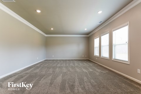 a empty living room with a carpeted floor and three windows