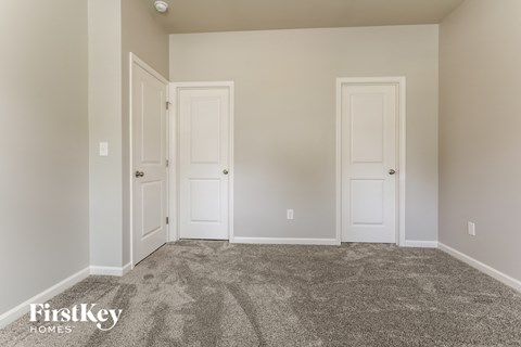 a bedroom with two doors and a carpeted floor