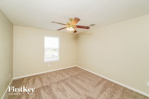 the spacious living room has carpet and a ceiling fan