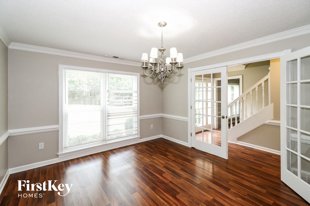 an empty dining room with wood floors and a chandelier