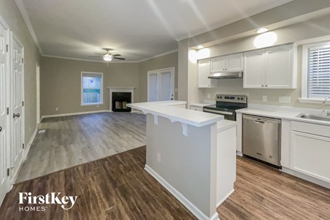 an open kitchen and living room with white cabinets and a white counter top