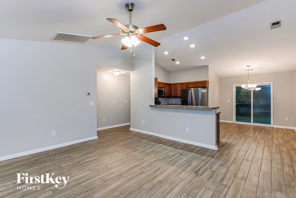 A spacious room with a bar and a ceiling fan.