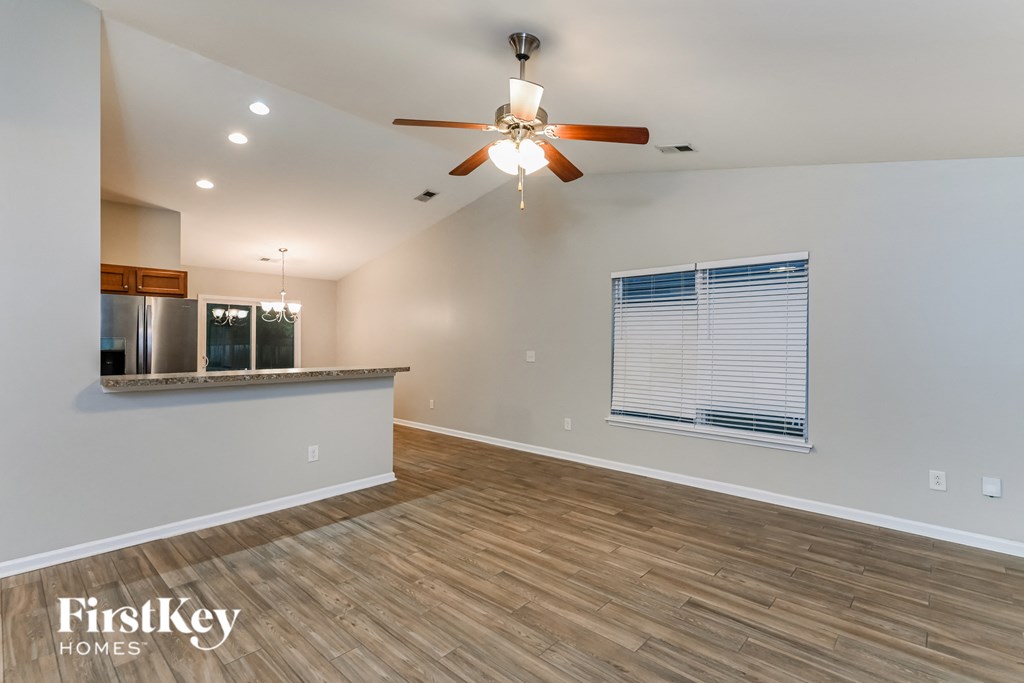A spacious room with a ceiling fan and wooden flooring.