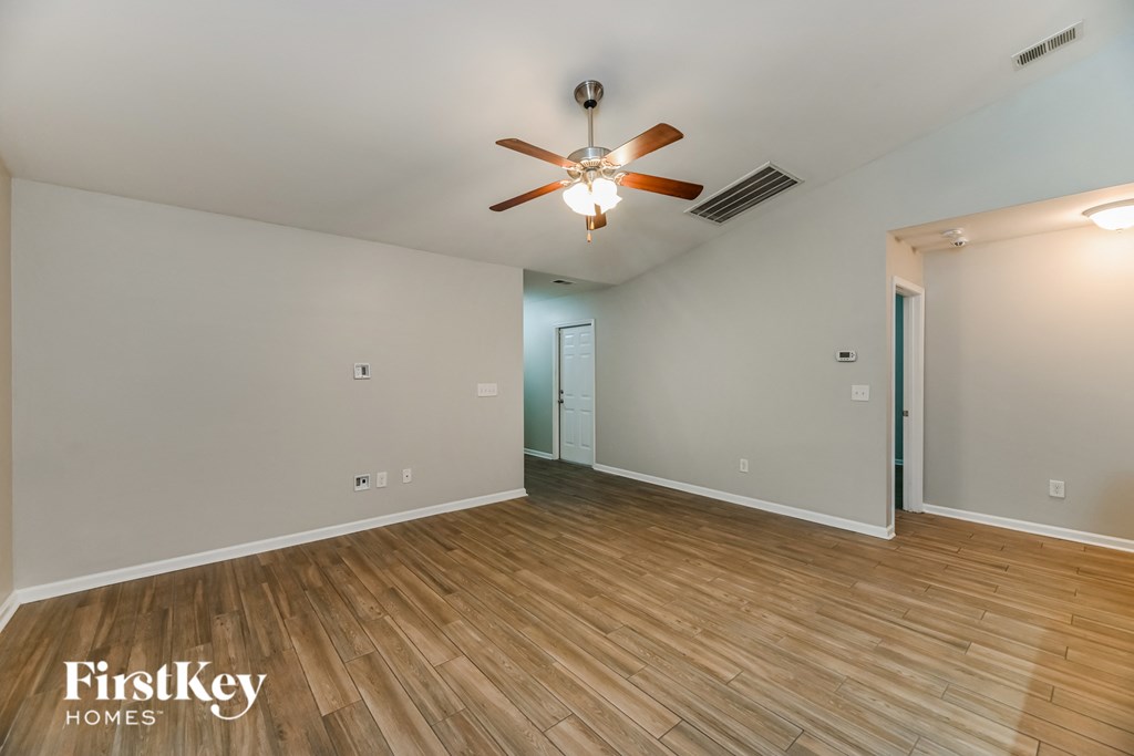 A room with a ceiling fan and wooden flooring.