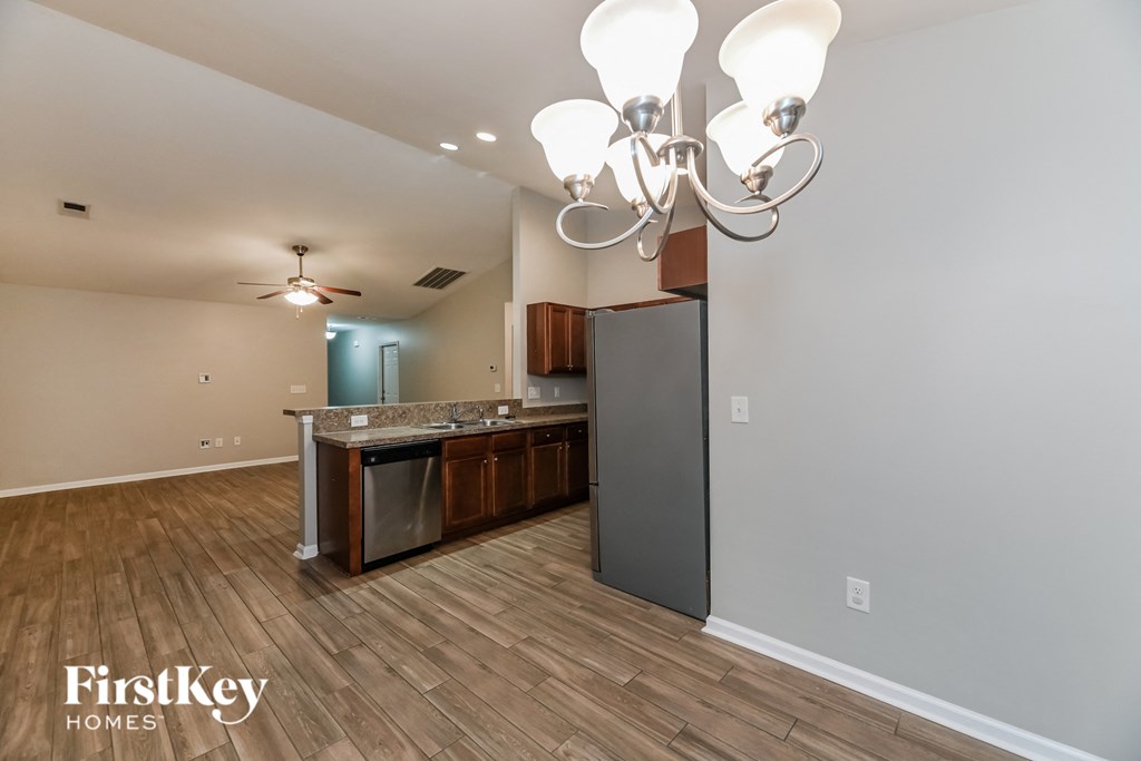 A well-lit kitchen with wooden floors and a chandelier.