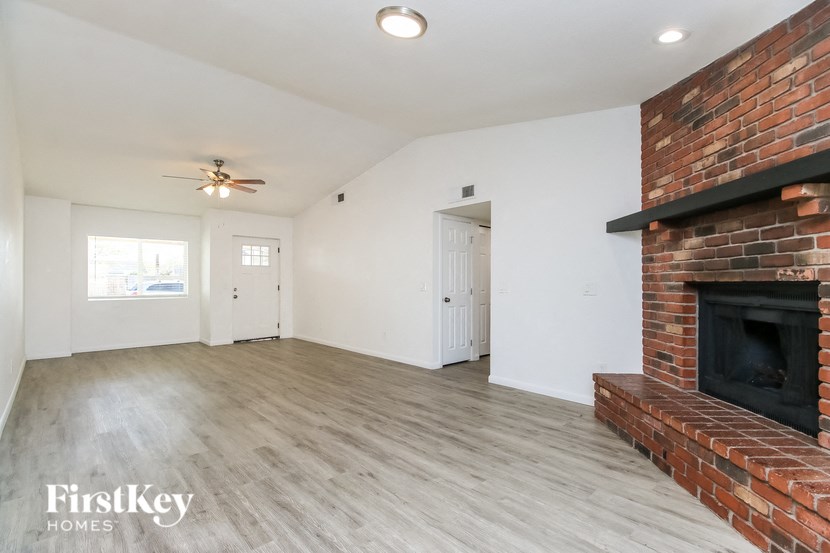 A spacious room with a brick fireplace and wooden flooring.
