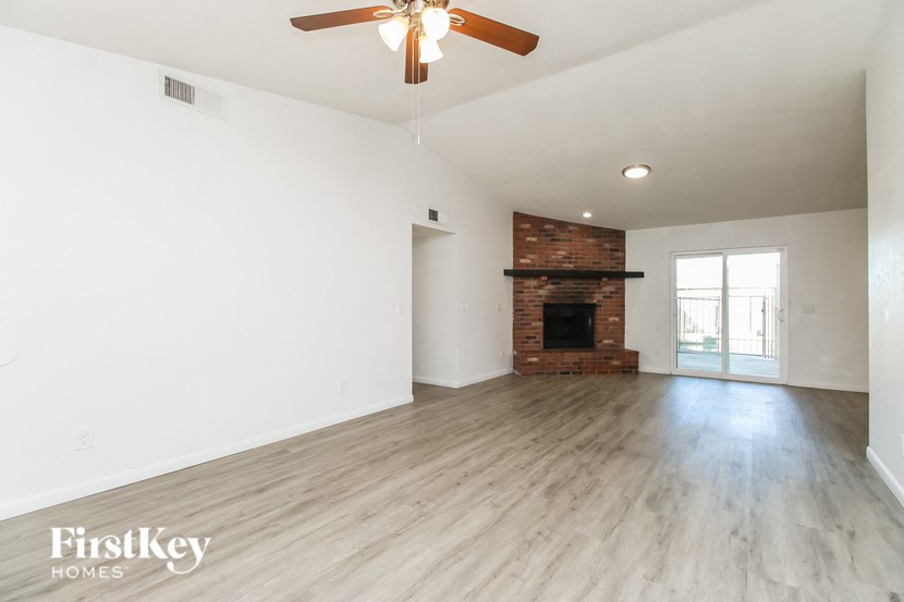 A spacious room with a fireplace and a ceiling fan.