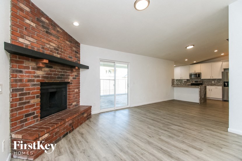 A room with a brick fireplace and wooden floors.