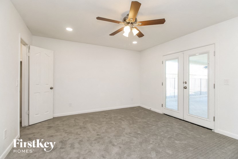 A room with a ceiling fan and two doors.