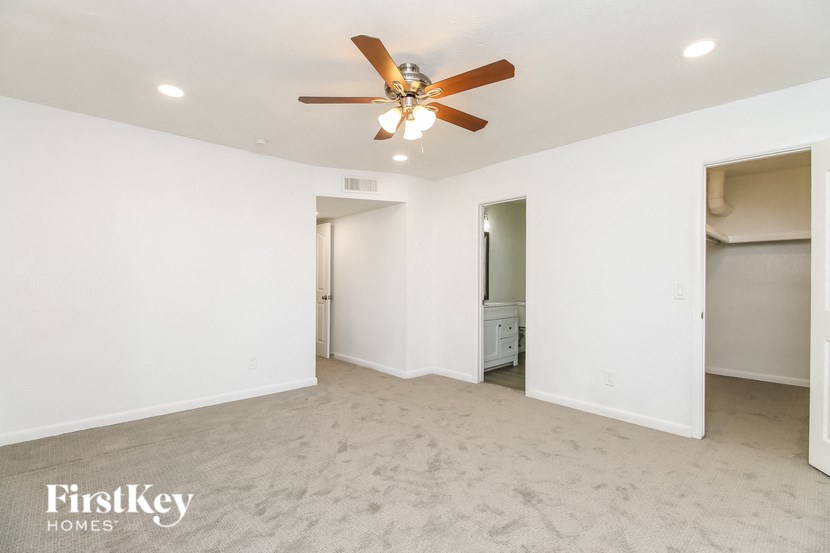 A spacious room with a ceiling fan and carpeted floor.