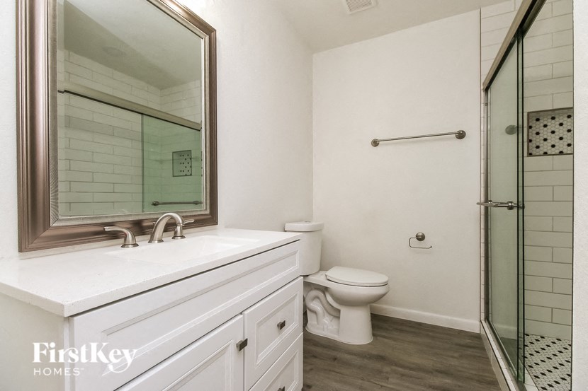 A white bathroom with a toilet, sink, and shower.