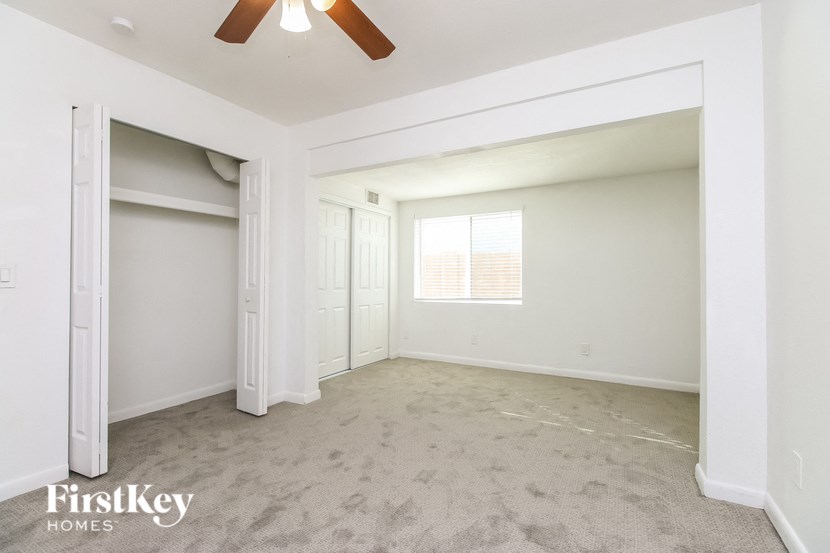 A spacious room with a ceiling fan and carpeted floor.