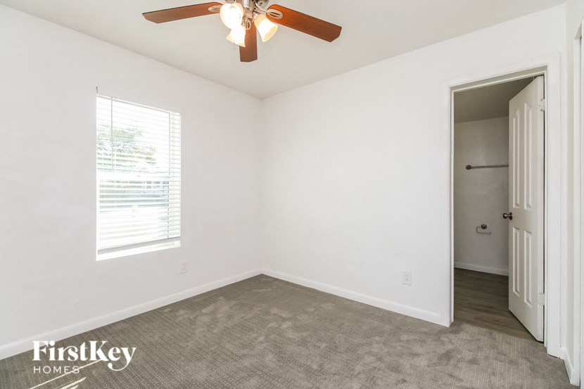 A room with a ceiling fan and a door leading to another room.