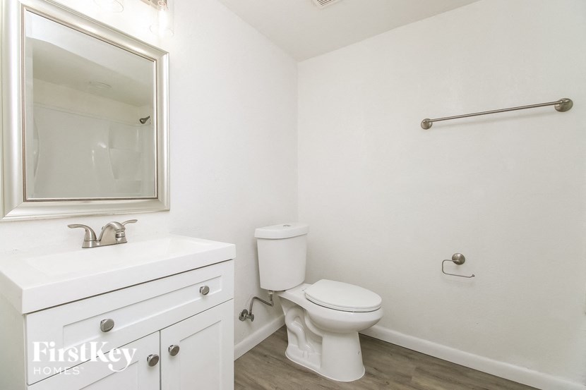 A white bathroom with a toilet, sink, and mirror.