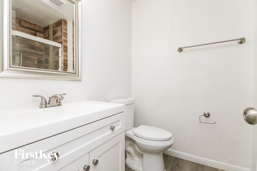 A white bathroom with a toilet, sink, and mirror.