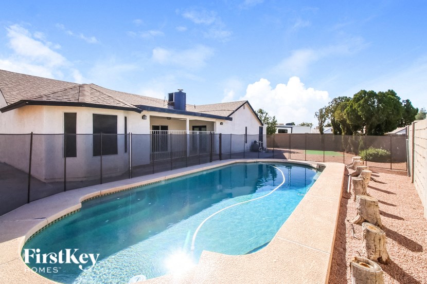 A swimming pool in a backyard with a house in the background.