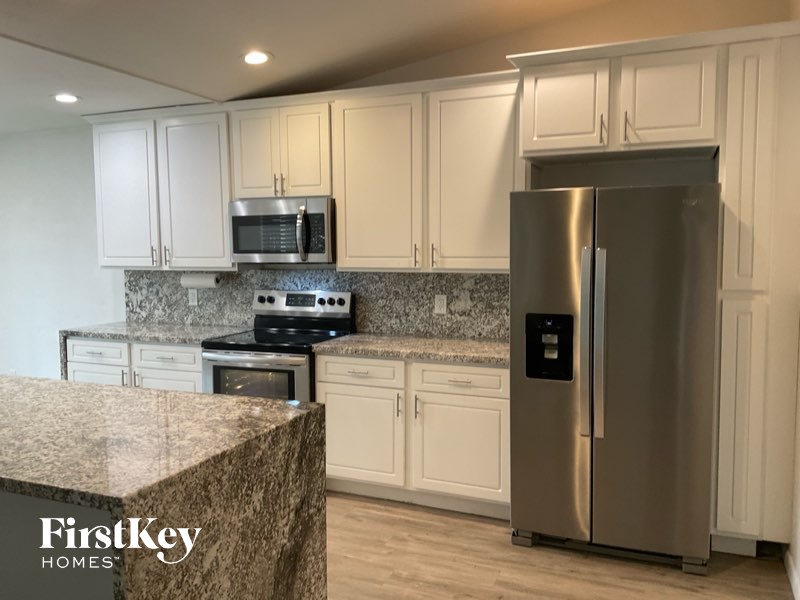 A kitchen with a granite countertop and stainless steel appliances.