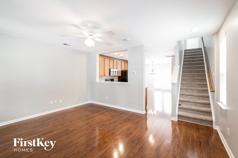 a living room with wood flooring and a staircase and a ceiling fan