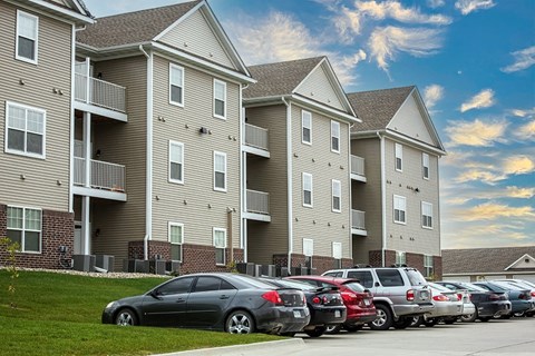 a row of apartment buildings with cars parked in front