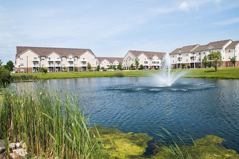 a pond with a fountain in front of some apartments