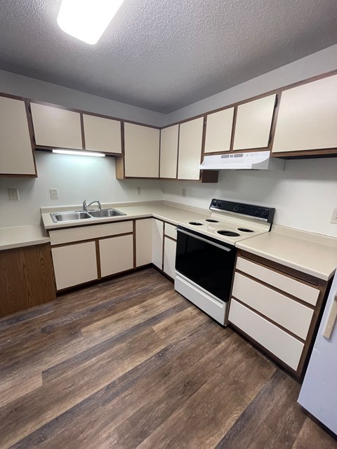 A kitchen with wooden floors and white cabinets.