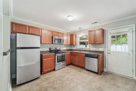 A kitchen with brown cabinets and a stainless steel refrigerator.