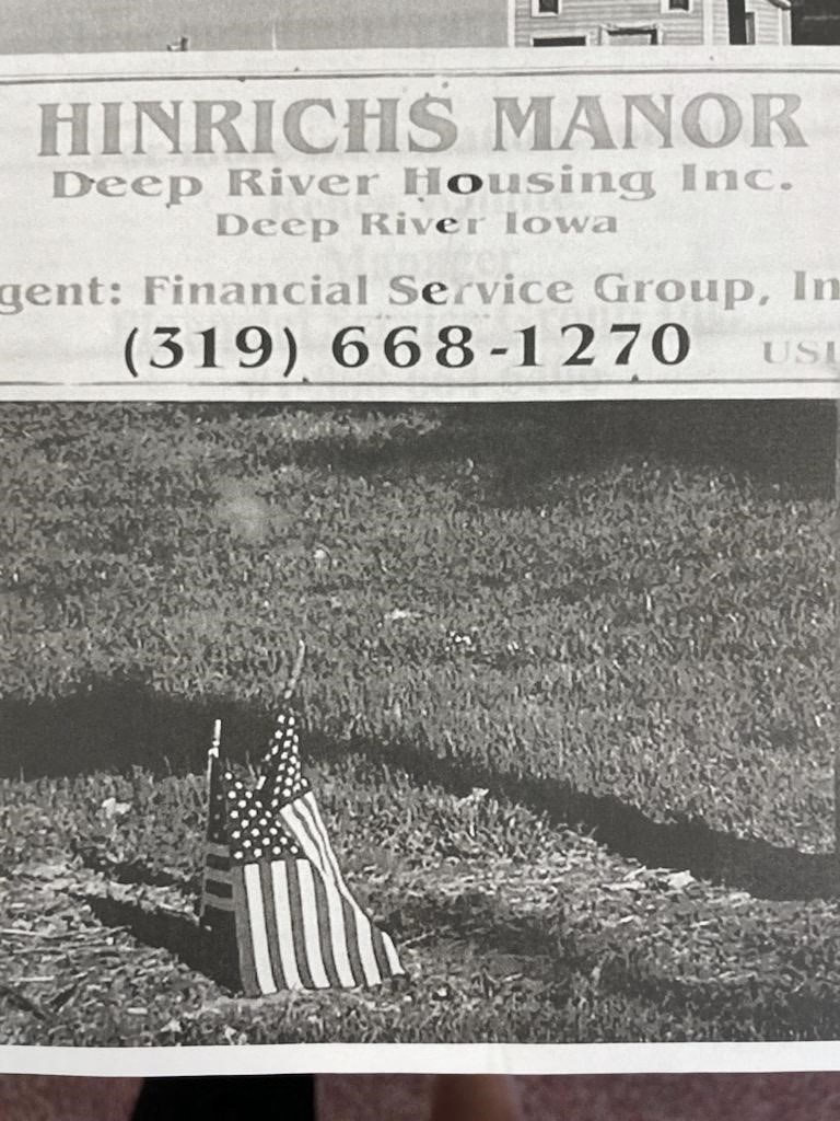 a flag laying in the grass next to a newspaper